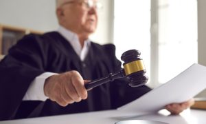 A judge reading a ruling as he starts to hit his gavel on the desk