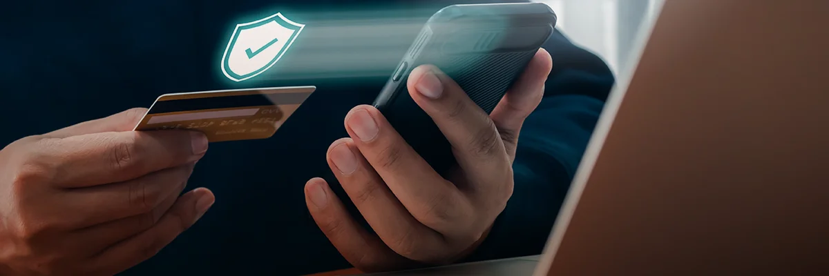 Person holding a smartphone and credit card with a digital security icon representing secure online gambling transactions