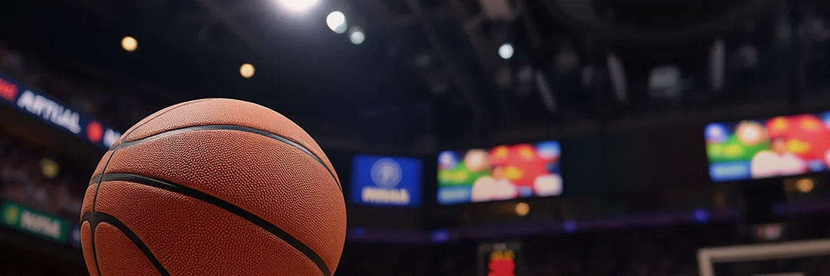 Close-up of a basketball on the court with an arena scoreboard in the background